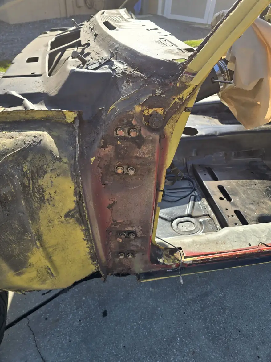 Classic project car body with old yellow paint and surface rust before blasting