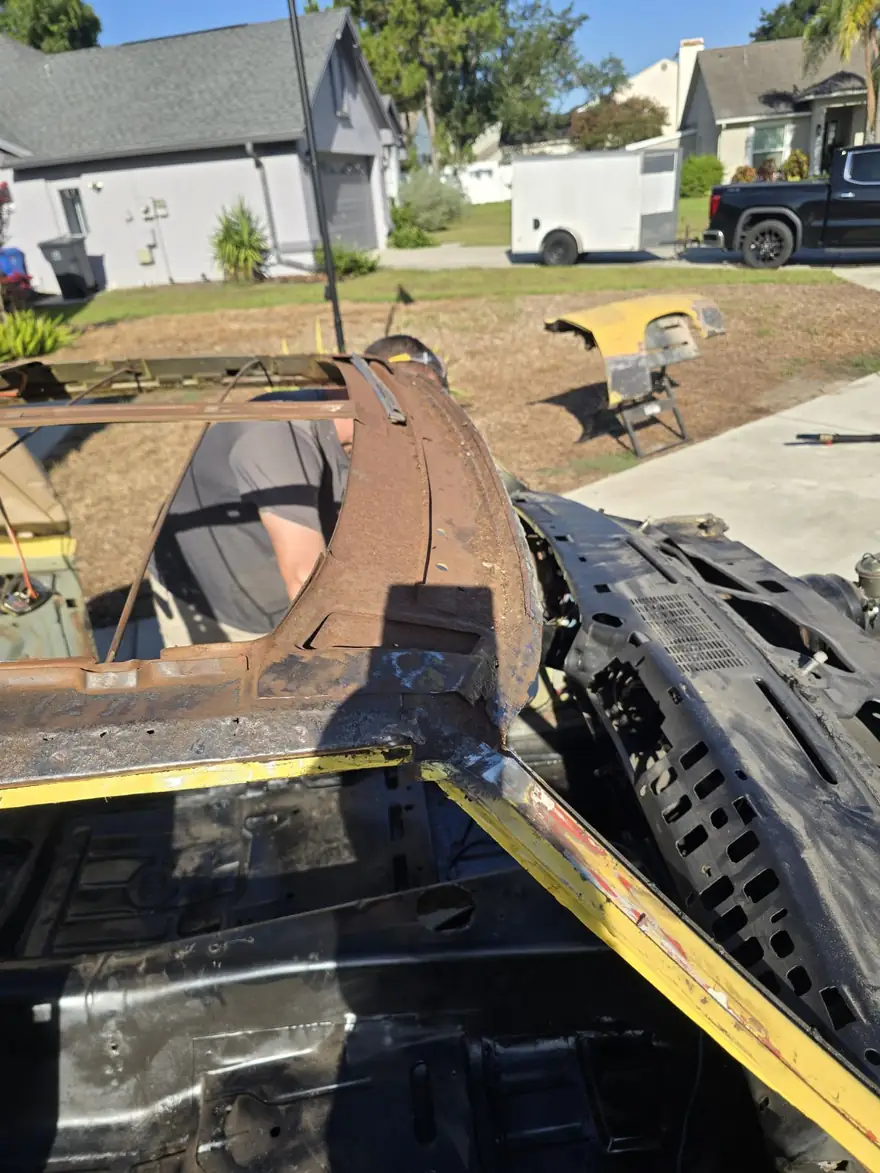 Rusted body section of a yellow project car before blasting