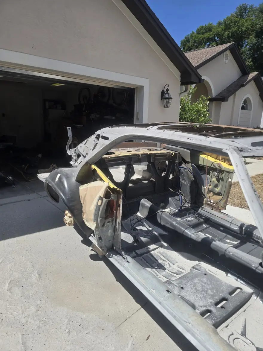 Whole project car shell stripped to bare metal in the driveway after blasting